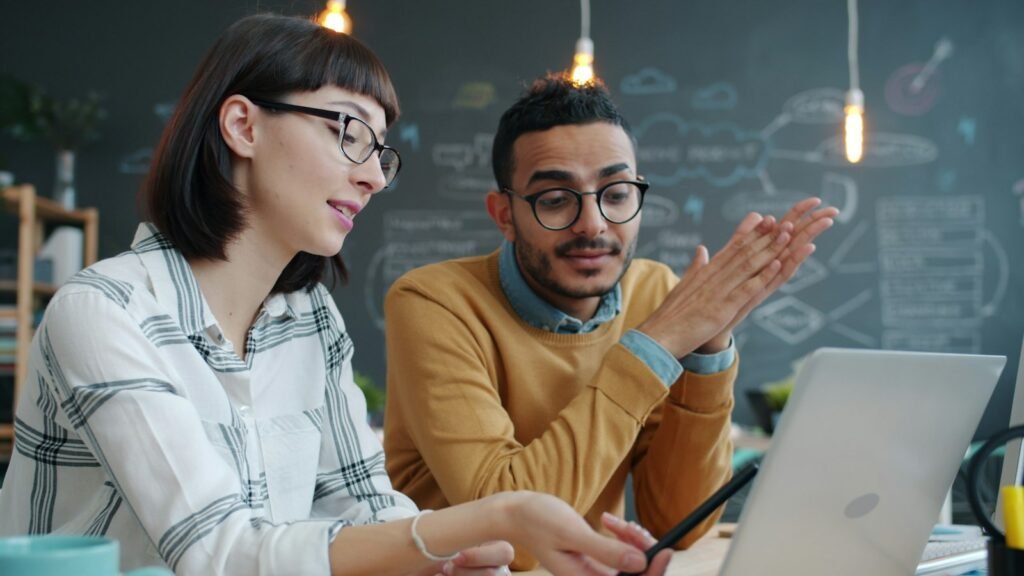 Two colleagues discussing a project while reviewing information on a laptop.